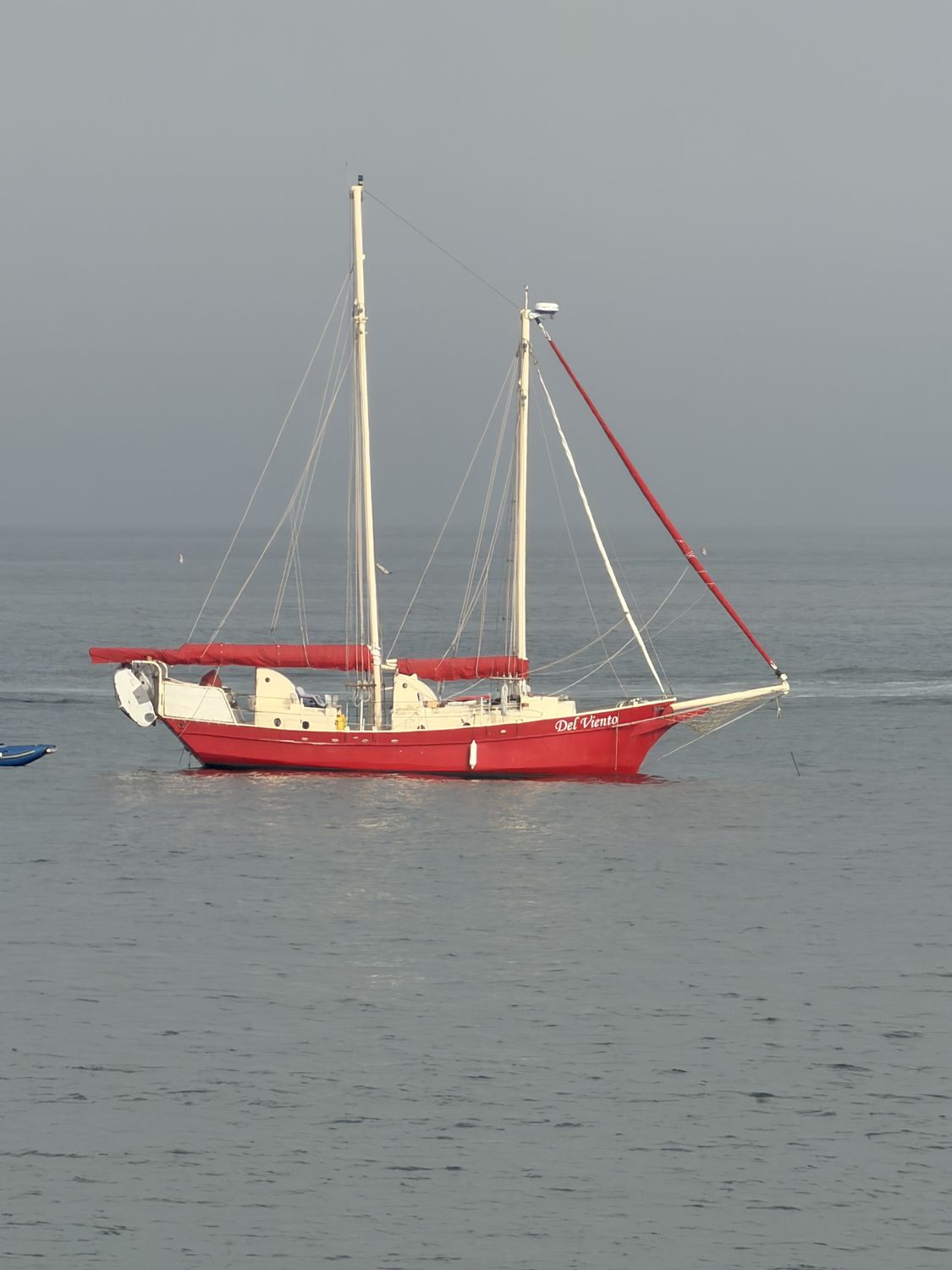 A red sailboat moored off the California coast