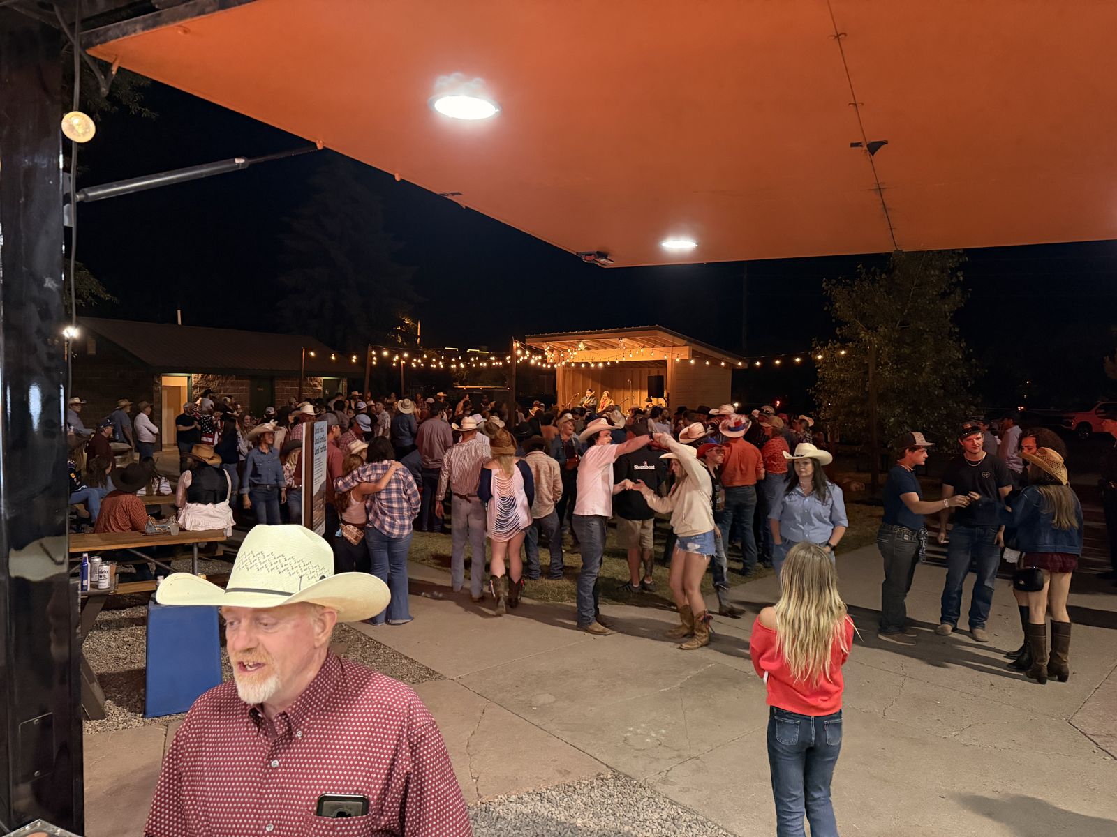 People two-stepping to a live band under string lights at the Steamboat Pro Rodeo grounds